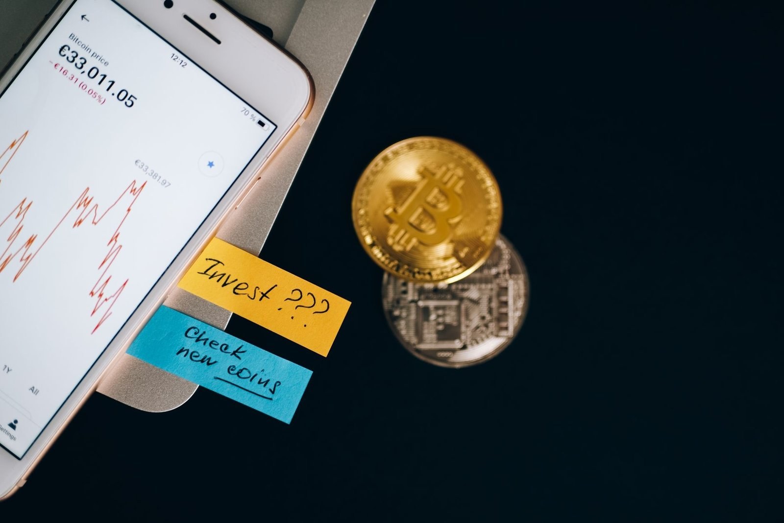Курс биткоина на экране смартфона рядом с золотой монетой