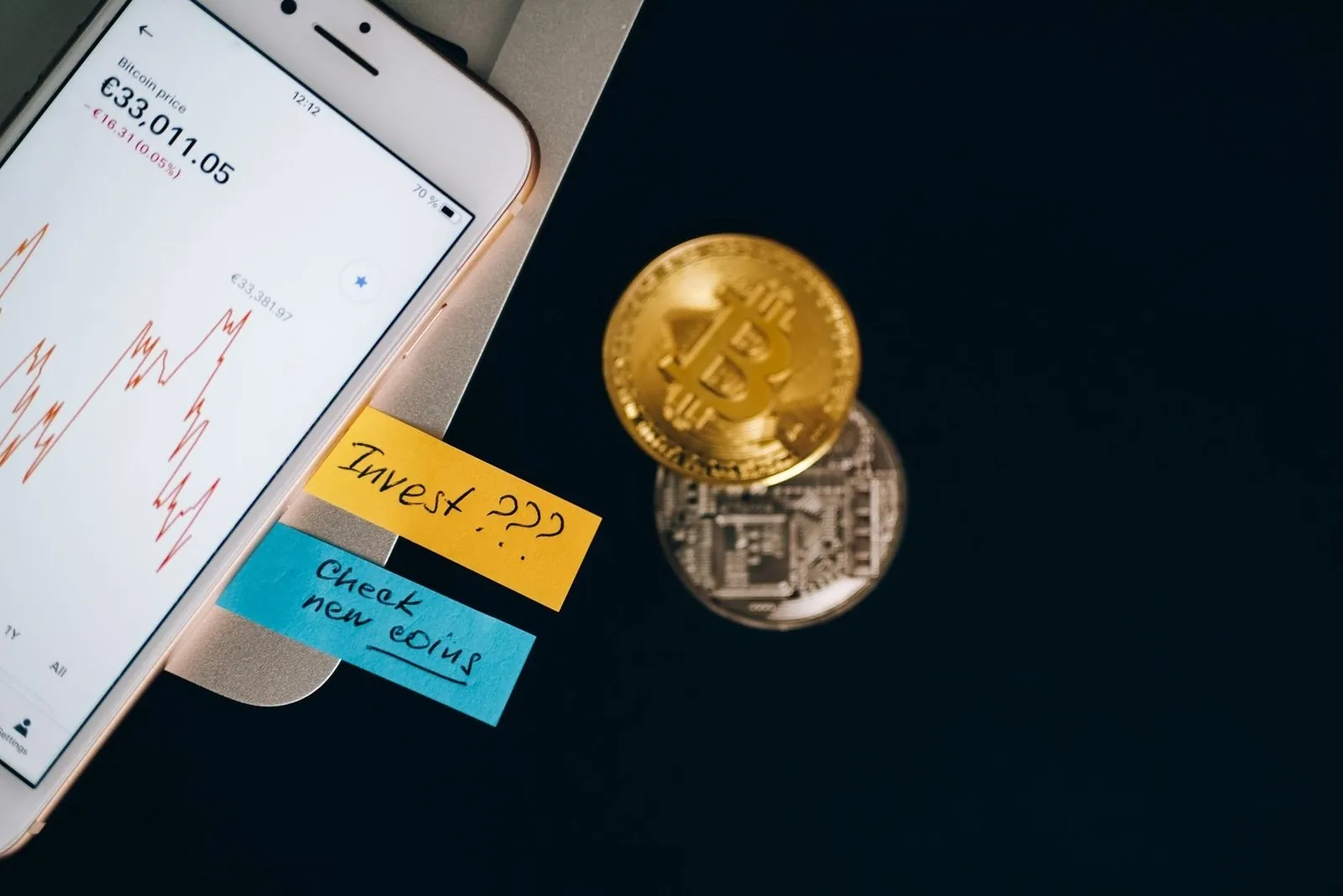 Курс биткоина на экране смартфона рядом с золотой монетой